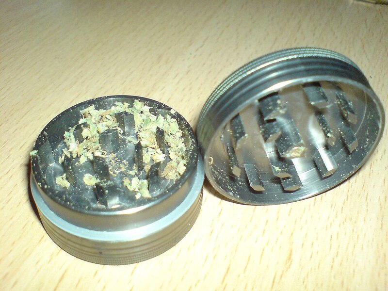Metal herb grinder opened showing teeth and ground cannabis